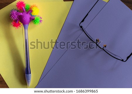 ballpoint pen with many colored pompoms on colored cardboard