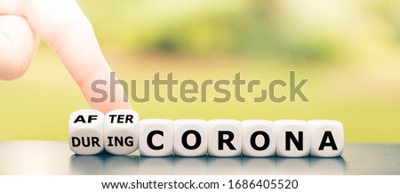Hand turns dice and changes the expression "during Corona" to "after Corona". Royalty-Free Stock Photo #1686405520