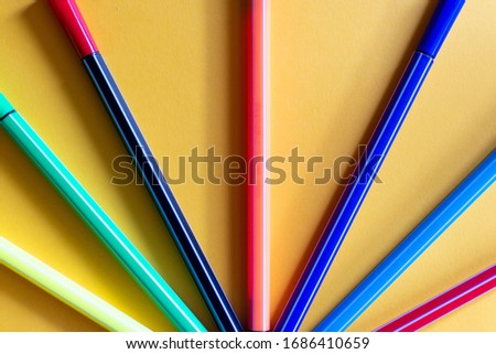 colored markers lined up on an orange cardboard