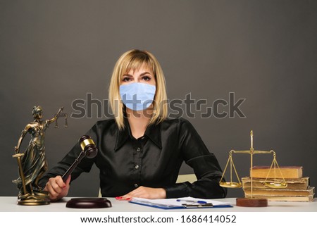 A young fair woman judge in protective mask works in her office. - image
