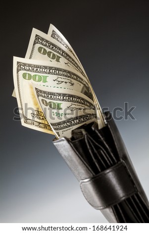 Dollar banknotes in leather wallet on dark background