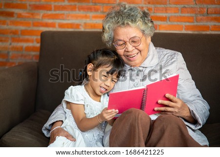 Closeup photo of Grandmother teaches to read a book her granddaughter,Family concept.