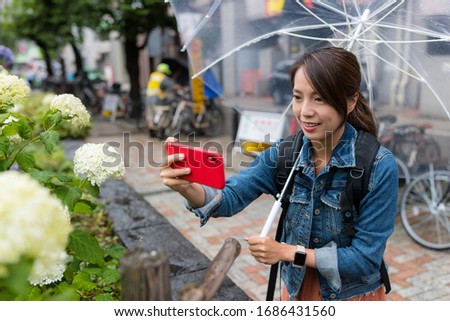 Woman take photo on flower at rain day