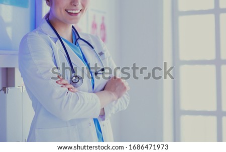Young woman medic in white uniform standing in clinic's office
