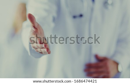 friendly male doctor with open hand ready for handshake