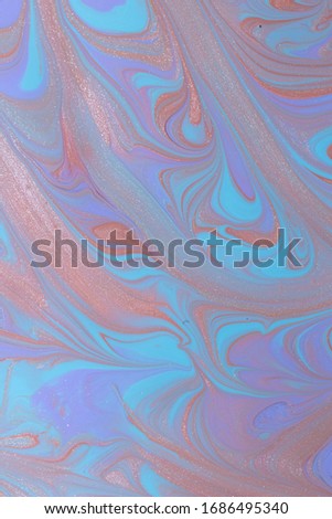 Abstract background of mixed shades of nail polish with a marble pattern and a shimmer. Creative watercolor blue, violet and bronze liquid colorful paint background