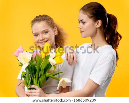 Cheerful Mom and daughter in a white T-shirt flowers holiday gift smile