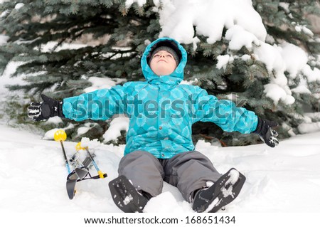 Boy with skis around snowy spruce