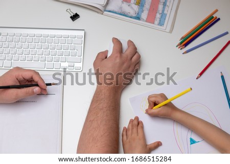 top view of a desktop with a working father and his child painting a picture. Coronavirus quarantine concept. selective focus