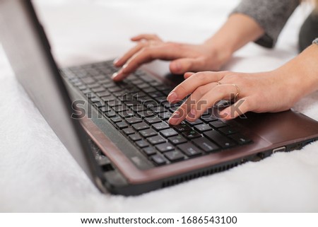 
Female fingers click on the buttons of a laptop, hands and computer, dusty laptop on a white background.