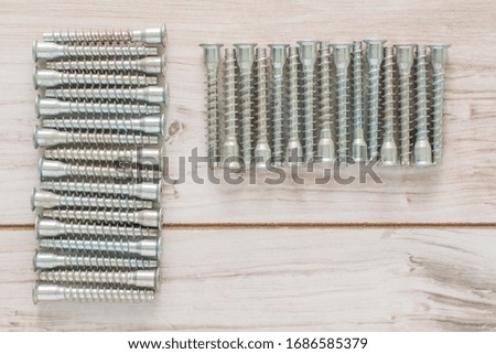 Group of Screw bolts for furniture assembling on wooden background. Flat lay top view with a copyspace for text. Stock photo