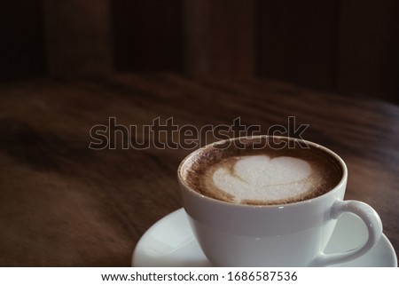 a cup of latte art on a table, photo has noise and gain