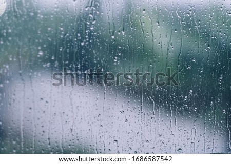 rain drops during raining in rainy day outside window glass with blurred background with water droplet flow down the surface Royalty-Free Stock Photo #1686587542