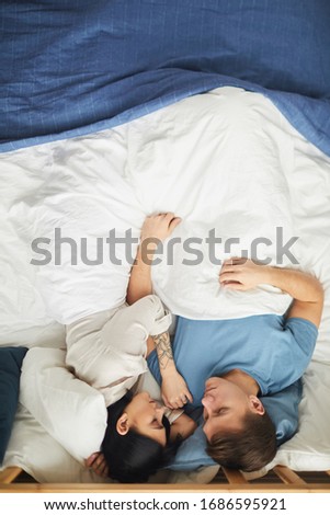 Above view at modern young couple sleeping together in blue and while bed sheets, copy space