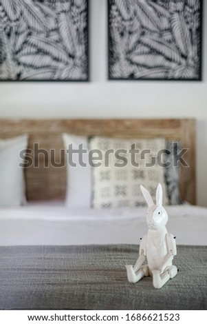 Vertical photo of white interior in cozy bedroom with selective focus at rabbit toy on bed in childrens room inside of elegant apartment