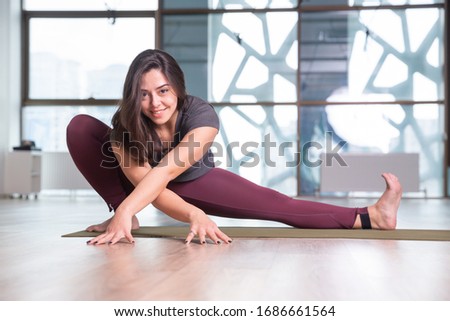 Photo of young woman practicing yoga indoor. Beautiful girl practice yoga in class. Yoga studio instructor. Blurred background