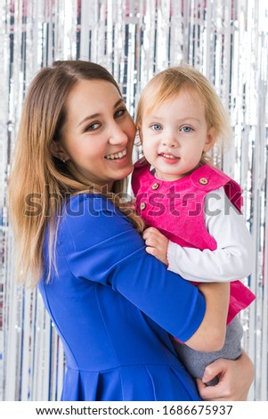 Childhood, love and family concept - Mother holds happy baby daughter on shiny background. Close-up