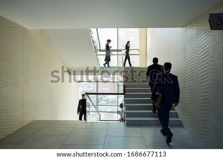Large group of young contemporary office managers going upstairs and downstairs in the middle of working day in business center Royalty-Free Stock Photo #1686677113