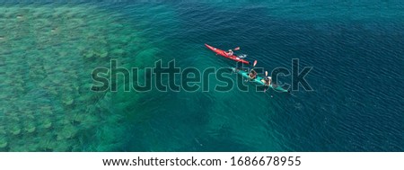 Aerial drone ultra wide photo of young couple canoeing in tropical exotic island bay