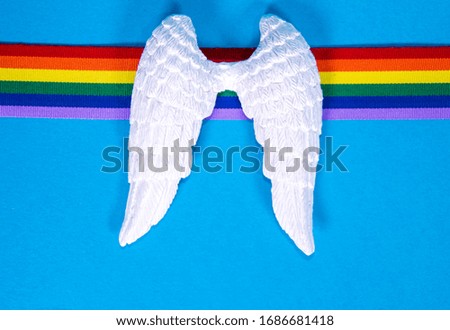 A set of white angel wings with a rainbow colored ribbon, to remember those who have died.