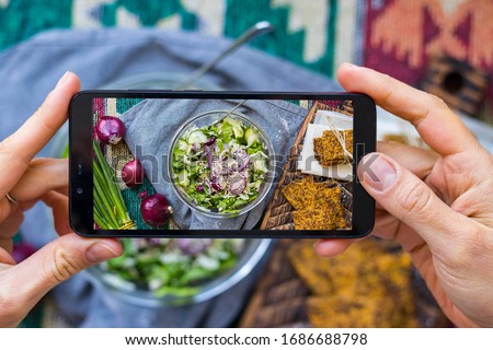 Phone picture of food. Hands make smartphone photography of vegetables detox salad for social media blogging. Concept for online order services. Vegan meal.