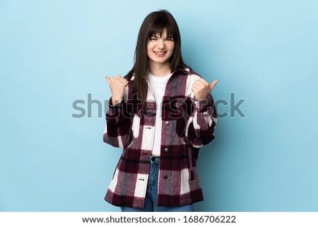 Teenager Ukrainian girl isolated on blue background with thumbs up gesture and smiling