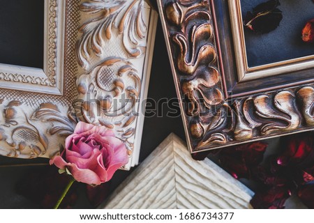 Details of empty picture art frames and flowers on dark backdrop. Framing workshop concept.