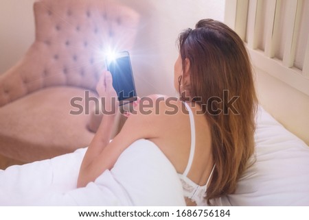 Young woman making selfie while lying on bed.