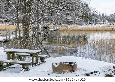 Public place to relax. Table and place for grill. Winter, snowy landscape. Finland. March 2020