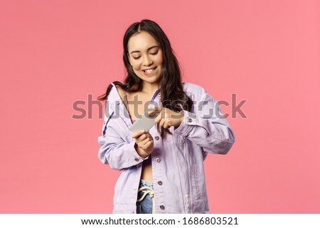 Online lifestyle, people and beauty concept. Portrait of stylish attractive young korean girl using mobile phone, eager to win and pass level in arcade, tilt smartphone as playing excting game Royalty-Free Stock Photo #1686803521