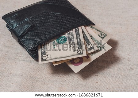 A dollar bill in the size 5 of a black wallet.