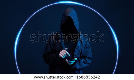 Dangerous hooded hacker. Internet, cyber crime, cyber attack, system breaking and malware concept. Anonymous. Dark background. Black minimalism.