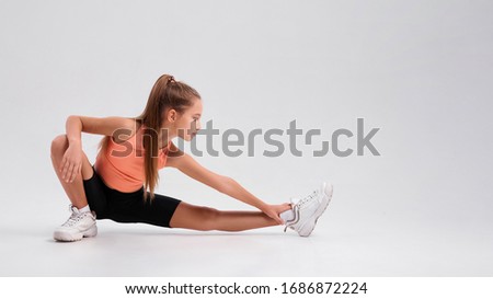 Flexible cute girl child looking at camera while stretching her body isolated on a white background. Sport, training, fitness, active lifestyle concept. Horizontal shot. Web Banner. Full-length