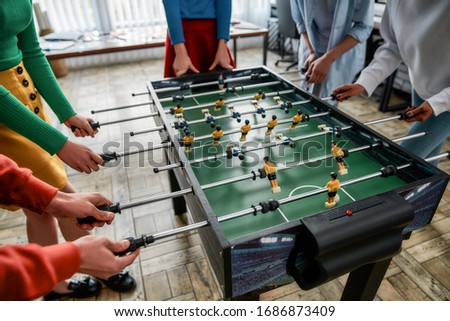 Cropped photo of young people playing table soccer in the office. Having fun together after work. Office activities Royalty-Free Stock Photo #1686873409