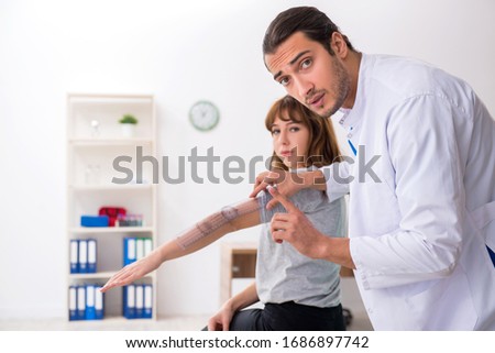 Young male doctor checking woman joint flexibility