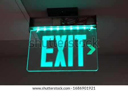 Glowing green exit sign, evacuation sign, safety sign, office building sign.
