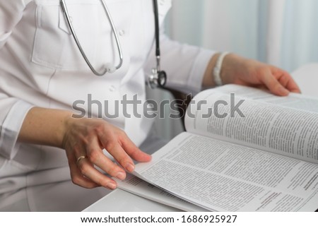 Hands of a female doctor holding a  medical journal in diagnostic cabinet. Doctor is waiting for patient. Stethoscope. Coronavirus. Royalty-Free Stock Photo #1686925927