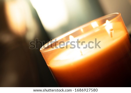 Angled Photo of A Lit Burning Three Wick Candle In A Glass Candle Jar