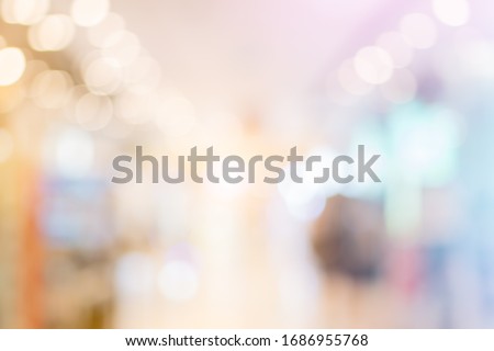 Blurred background with bokeh light in luxury fashion shopping mall with shop window and display modern model  from stores with women and men customer walking in walkway hallway in department 