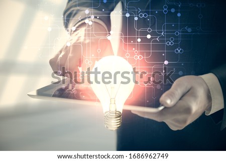 Double exposure of man's hands holding and using a digital device and bulb hologram drawing. Idea concept. Royalty-Free Stock Photo #1686962749