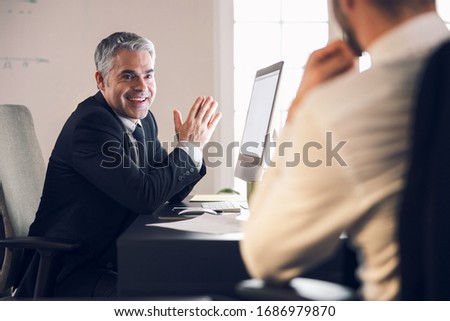 Happy male office workers sharing news in office stock photo. Business concept