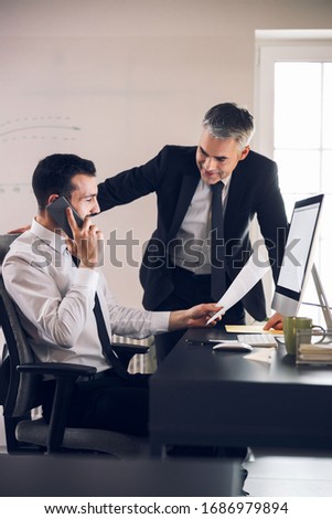 Happy colleagues talking to each other in office stock photo. Business concept