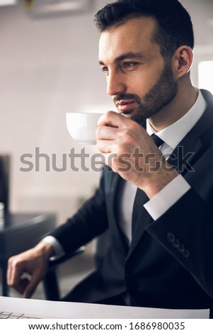 Calm businessman enjoying warm tasty beverage during coffee break stock photo. Business concept