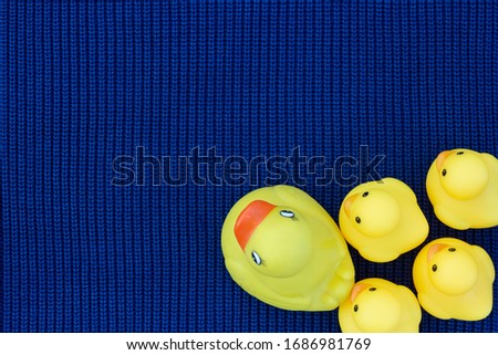 Rubber duck on blue fabric. Toy Cartoon bird background. Baby fabric texture.