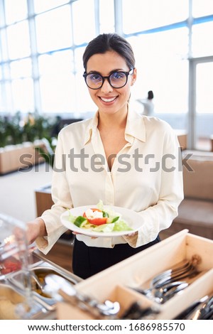Attractive young woman choosing food in cafeteria and smiling stock photo