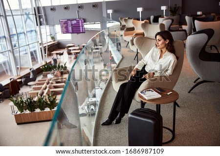 Attractive elegant lady resting on the second floor of airport waiting room stock photo