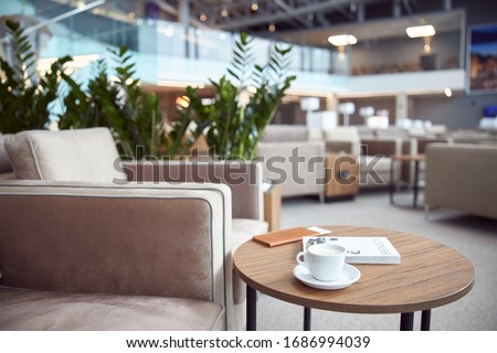 Round desk with business literature, cup of hot drink and wallet at airport waiting room stock photo Royalty-Free Stock Photo #1686994039