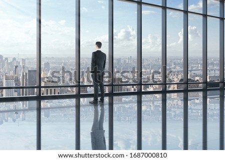 Businessman looking out of window in office interior with panoramic city view. Research concept.