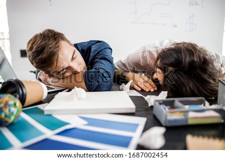 Young coworkers sleeping at work after a hard day in the office stock photo. Teamwork concept