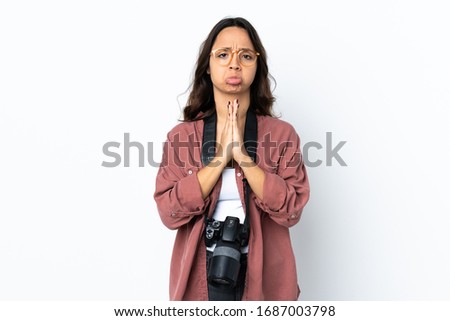 Young photographer woman over isolated white background keeps palm together. Person asks for something